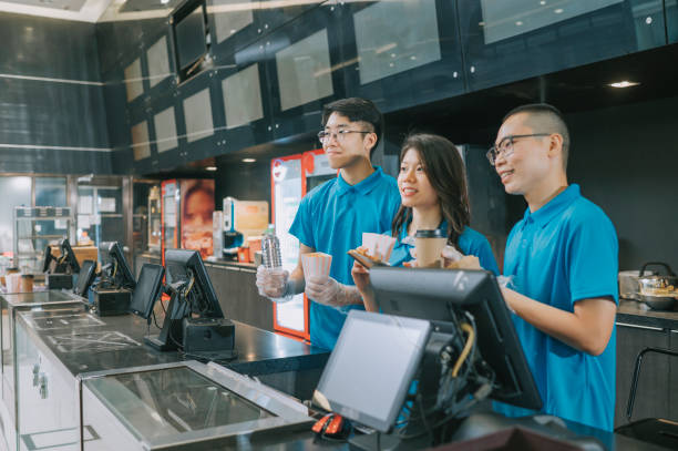 istock portrait asian chinese fast food worker with uniform looking at camera smiling in front of concession stand at movie theater cinema 1328701644