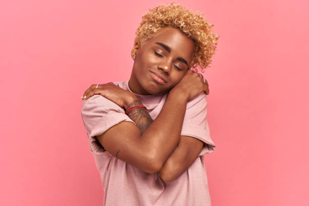 istock Charming gorgeous Afro woman satisfied emotion, hugs herself, keeps eyes closed 1328702931