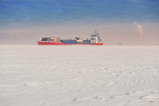 Winter shipping. Big cargo ship in frozen ice sea fairway