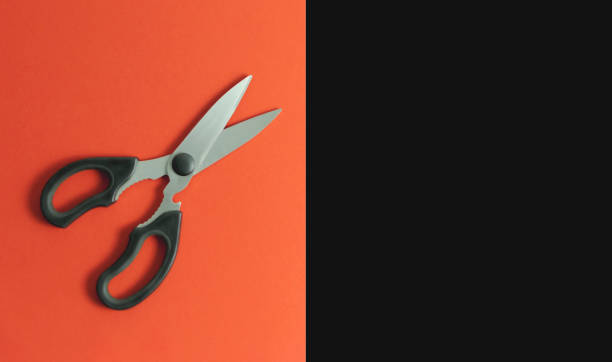 istock Open scissors on red and black paper background 1328723380