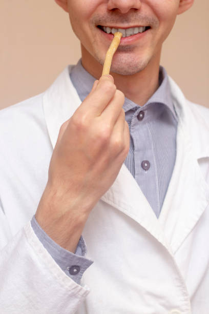 istock A young man brushes his teeth with a miswak (siwak) in a white coat. arak tree, Salvadora persica, sunnah. Beige background. 1328725629