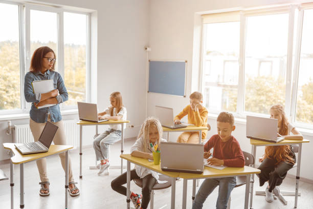 istock Schoolchildren sitting at desks and using laptops 1328727317