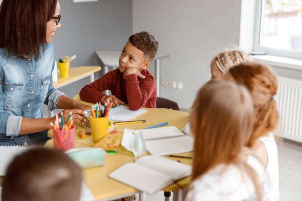 istock Smiling teacher having a lesson with kids in the classroom 1328727363