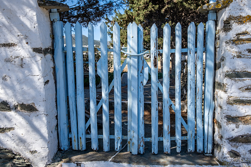 Greece. Cyclades. Blue painted wooden fence gate closed. Typical entrance to house front yard, summer sunny day at Sifnos island,