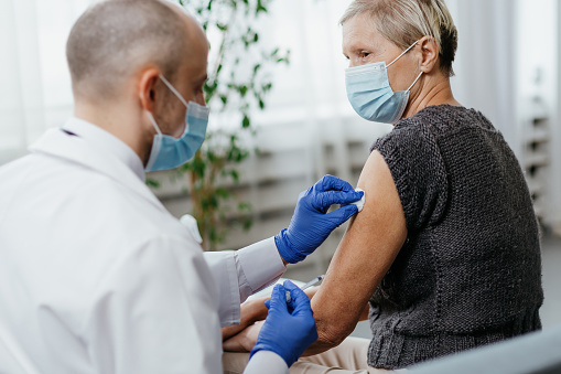 mujer con mascarilla protectora es vacunada en un consultorio médico photo