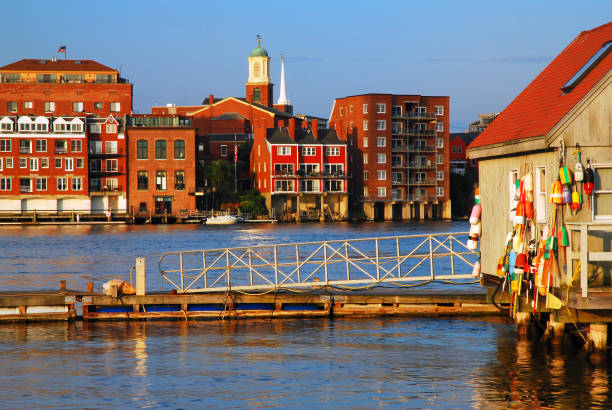 A rustic seaside shack with colorful lobster buoys contrasts with the new waterfront development of Portsmouth, New Hampshire