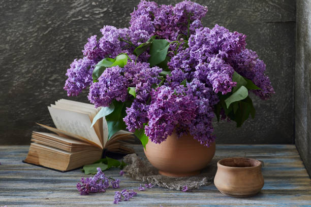 nature morte. bouquet lilas dans une cruche en argile et un livre ouvert sur une table en bois. style rustique. - flower pot vase purple decor photos et images de collection