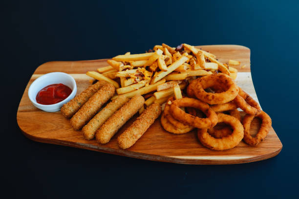 onion rings and mozzarella sticks with french fries in the restaurant - mozzarella stick appetizer fried imagens e fotografias de stock