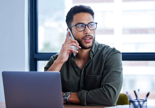 istock Shot of a young businessman talking on a cellphone while working in an office 1328736881