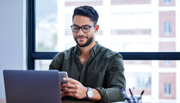 istock Shot of a young businessman using a cellphone while working in an office 1328737099