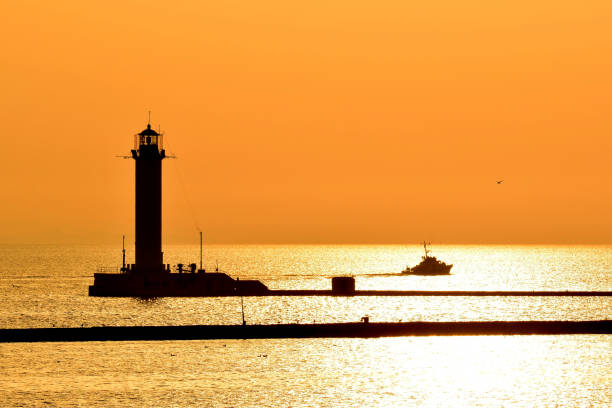 istock Patrol boat and lighthouse silhouettes at sunrise 1328737862