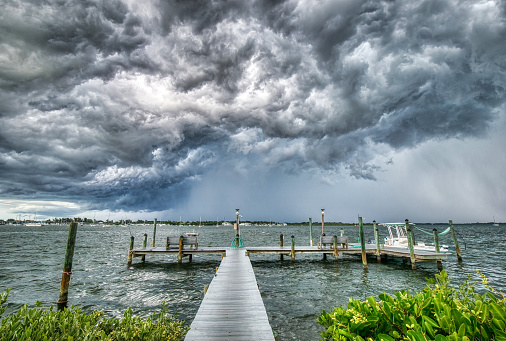 Threatening storm coming across the Intracoastal Waterway in Bradenton Beach, FL with a dock with a boat moored in the foreground.
