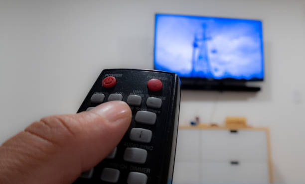 istock hand with tv remote control points to tv screen 1328743864