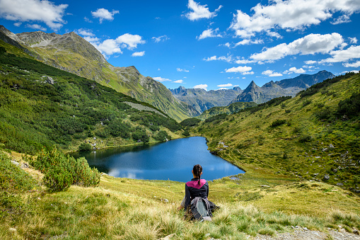 Woman resting from hiking in a landscape with a beautiful small lake in the mountains