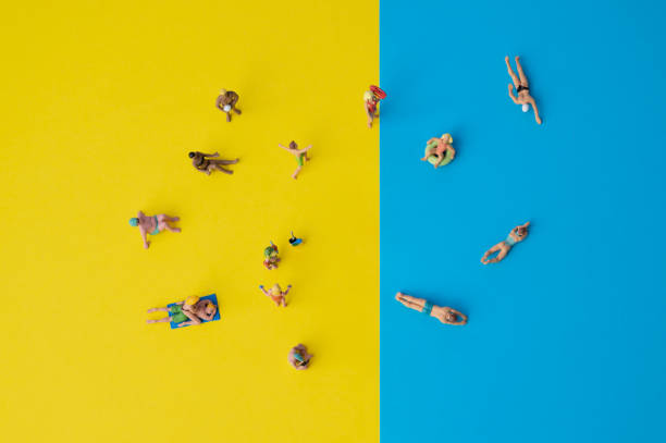 personas en miniatura en papel amarillo y azul, situación de vacaciones con personas que nadan o que toran el sol - figurita fotografías e imágenes de stock