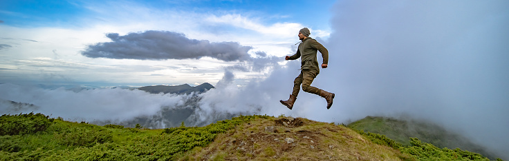 The man running on the mountain on a cloudy sky background