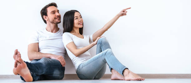 istock The couple gesturing on the floor on the white wall background 1328751061