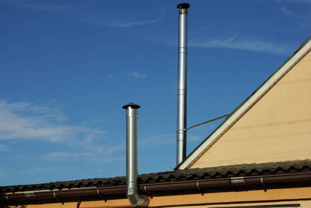 istock two gray metal chimney pipes on the brown roof 1328753402