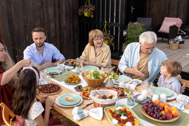 Grandfather Talking to Grandson Grandfather talking to little grandson at family reunion dinner big family table stock pictures, royalty-free photos & images