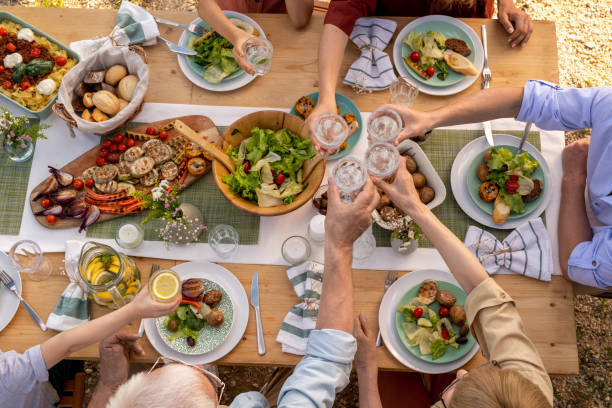 People Toasting with Glasses of Water Group of people toasting with glasses of fresh water over dinner table with tasty healthy food family reunion celebration stock pictures, royalty-free photos & images