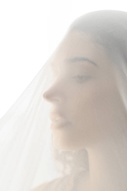 istock Attractive young brunette bride wearing wedding veil on face agains bright light 1328757098