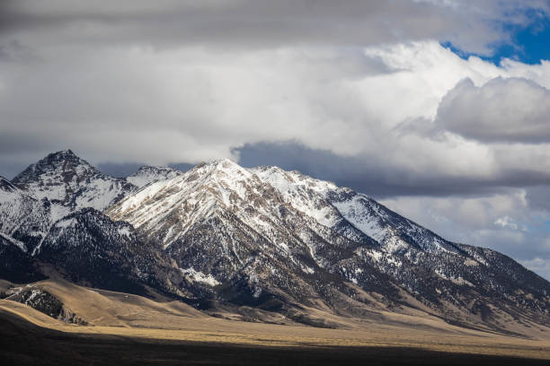 istock Distant snow covered mountain peaks with white clouds and blue skies 1328757695