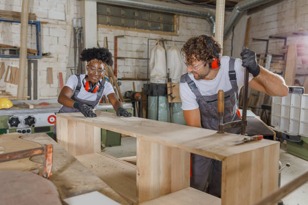 istock An Experienced Carpentry Worker and His Female African Coworker are Using a Clamp While Working in a Large Workshop. 1328759304