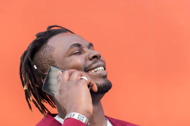 istock stylish black man laughing and talking on phone 1328765273