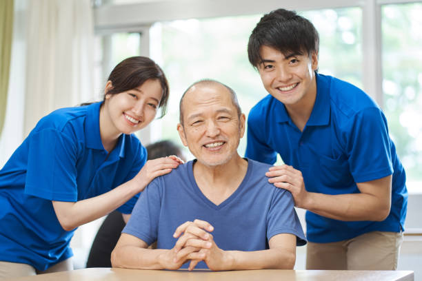 un anziano sorridente e un caregiver di supporto - nursing home senior adult group of people home caregiver foto e immagini stock