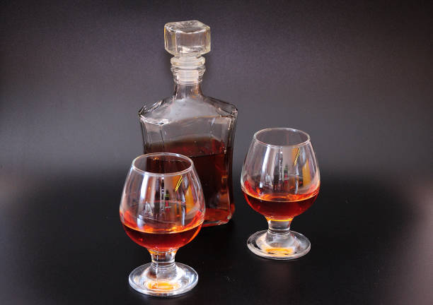istock Glass bottle and two crystal glasses with cognac on a black background. 1328776643