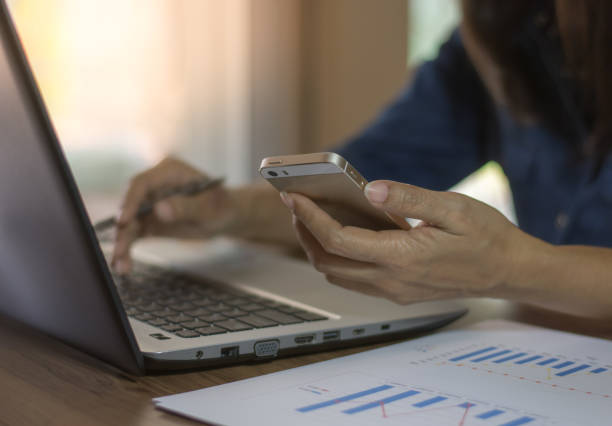 istock Business woman using mobile phone and work on laptop computer. 1328780127