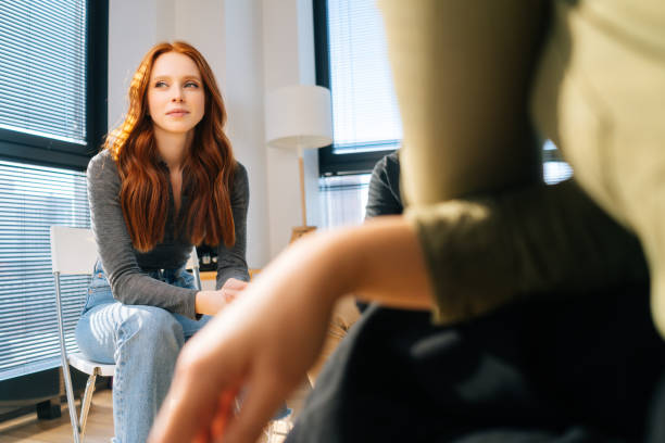 istock Sad young woman sharing mental problem to other patients sitting in circle during group therapy session. 1328780278
