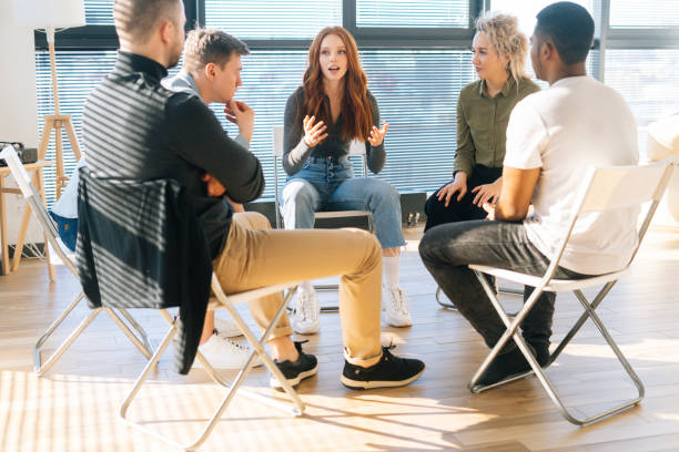 istock Diverse young colleagues sitting in circle have fun talking on business training with coach by window in light office room. 1328781152