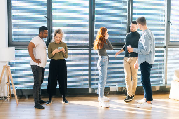 istock Front view of young multiethnic coworkers having fun conversation during coffee break in modern office. 1328782723