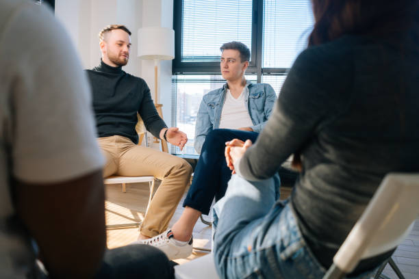 istock Emotional young man telling about his mental problem or addiction to other patients sitting in circle. 1328783608
