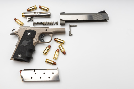 Parts of 1911 gun model and .45 bullets on white background