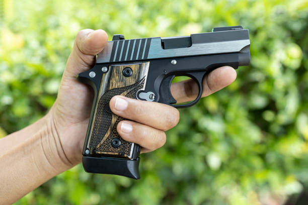 istock Automatic pocket gun or concealed pistol in her hand on nature background 1328784569