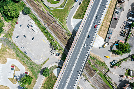 aerial top view of car traffic on road bridge crossing a railway in urban industrial area