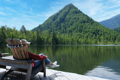 Woman sitting in a chair resting on a beautiful forest lake
