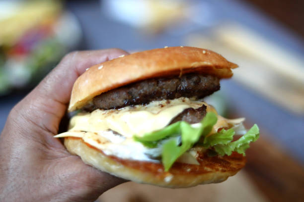 maintenez hamberger manger burger de bœuf avec des frites dans un restaurant de restauration rapide en plein air. mise au point sélective flou d’arrière-plan avec espace de copie - burger gourmet hamburger steak photos et images de collection