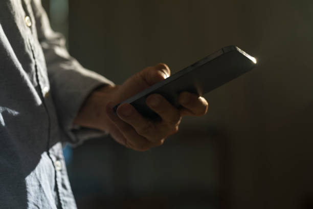 istock Close-up of man using mobile phone on dark background. 1328797132