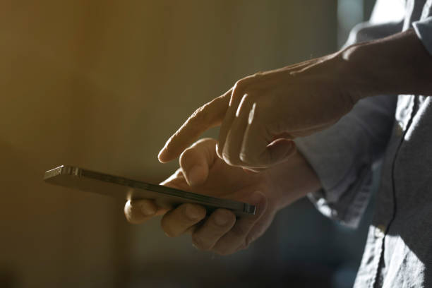 istock Close-up of man using mobile phone on dark background. 1328797133