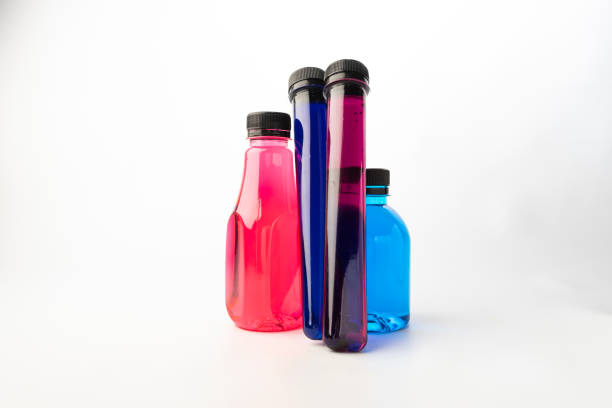 istock Plastic bottles and test tubes filled with colorful liquids on white background. Plastic containers filled with Blue, Navy blue, Pink and Purple food coloring 1328800857