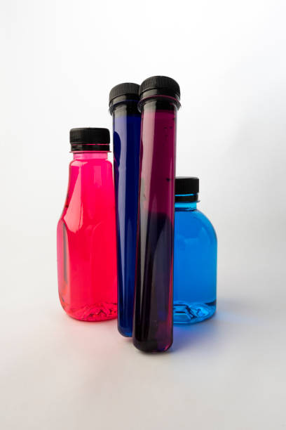 istock Plastic bottles and test tubes filled with colorful liquids on white background. Plastic containers filled with Blue, Navy blue, Pink and Purple food coloring 1328800876