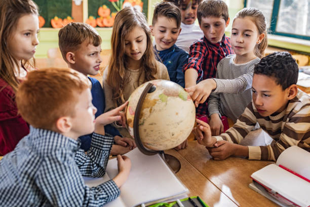 istock Large group of students analyzing globe in the classroom. 1328803293