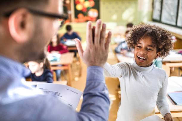 istock Happy black schoolgirl giving her teacher high-five on a class. 1328803412