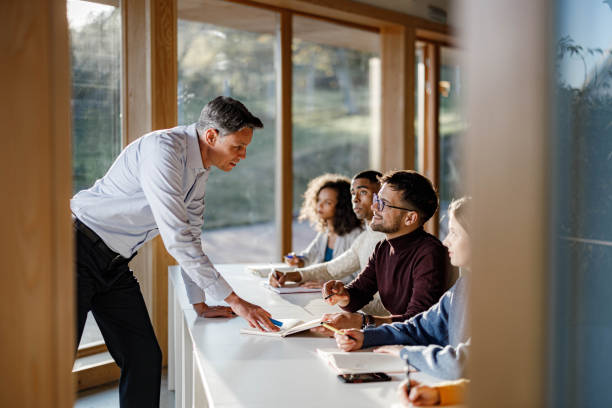 istock Happy teacher assisting his student on a class in the classroom. 1328805370
