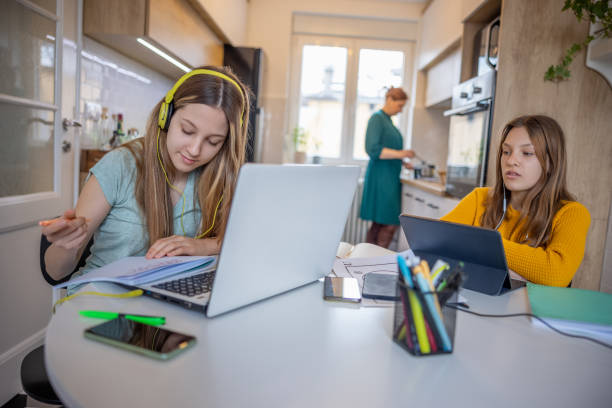 istock Teenage sisters using portable information devices for remote learning, mother working at home 1328807885