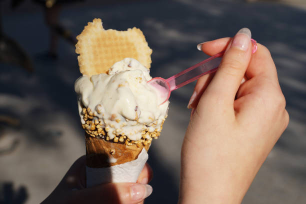 istock girl eating ice cream in a waffle cone hands close up 1328809861
