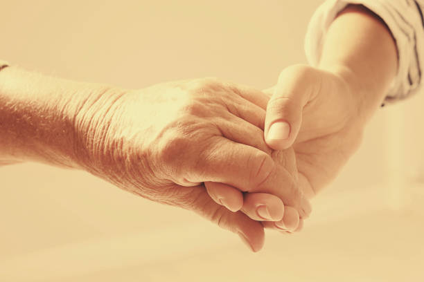 istock Helping hands on beige background, closeup. Elderly care concept 1328810011
